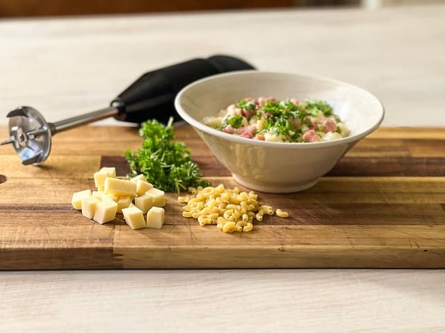 En sort stavblender ved siden af ingredienser og en skål