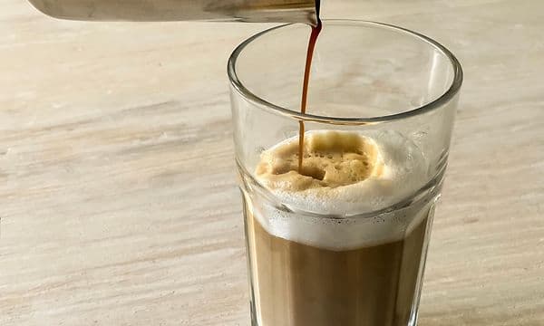En latte der bliver skænket op i et glas