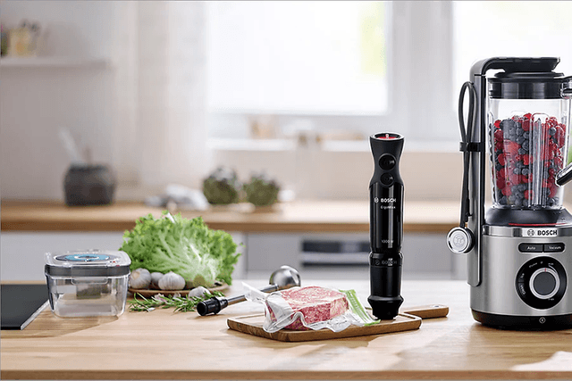 Olika produkter för vakuumförvaring som vakuumpåsar, boxar, stavmixer mm framställda på ett bord. 