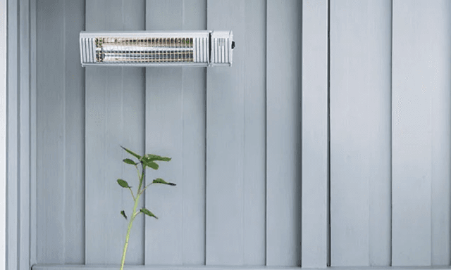 Veggmontert terassevarmer over grønn plante og sofa