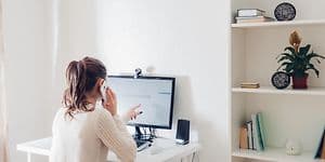Kvinde, som arbejder hjemmefra foran PC med eksternt webcam