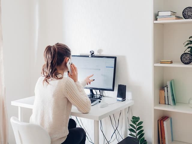 Kvinne på hjemmekontor foran PC med eksternt webkamera