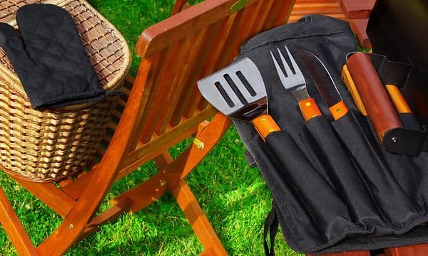 Grillredskaber ved siden af en grill på en baggrund af grønt græs