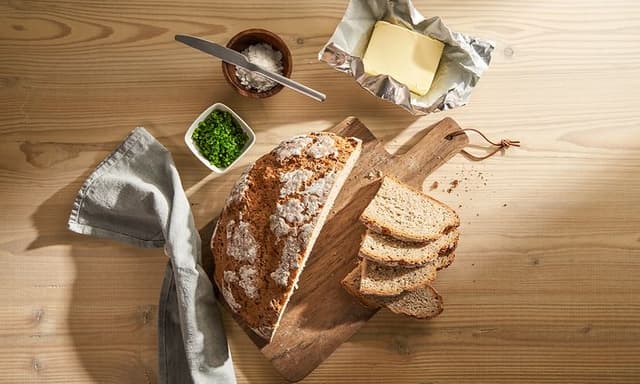 Ferskt surdeigsbrød servert på et bord med smør sett ovenfra