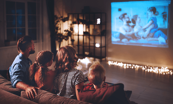 Hjemmebiograf med projektor: Familie, der ser en film gennem projektor på en skærm