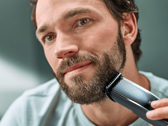 Mand der barberer sit skæg med en shaver