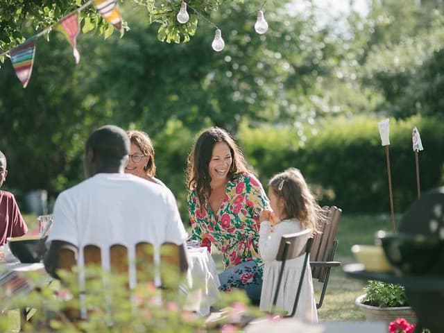 Several people sitting outside around a table eating