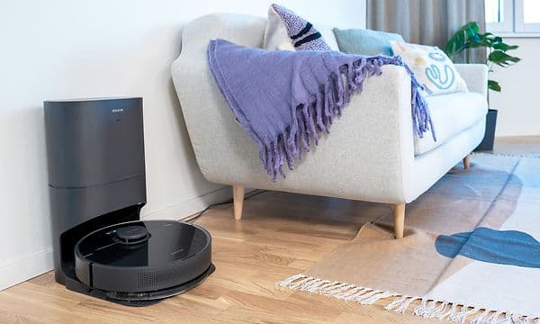 Dreame DreameBot  D10sPlus robotsøvsuger i ladestasjon ved siden av sofa