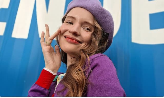 Ung jente med en lilla beret smiler til kameraet