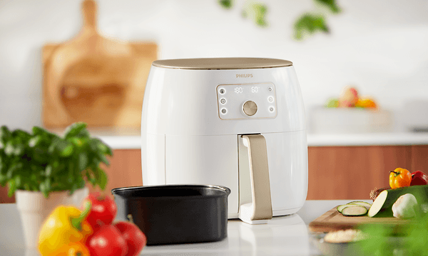 Hvit Philips Airfryer XXL og ferske grønnsaker og basilikum ved siden av