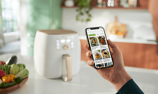 Hvit Philips Airfryer XXL på et bord og en person som bruker nutriU-appen