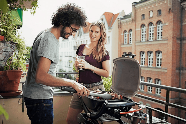 Pariskunta grillaa parvekkeella