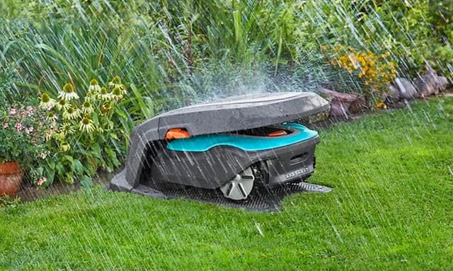 Robotplæneklipper der sidder i ly for regnen i et Gardena-overdække