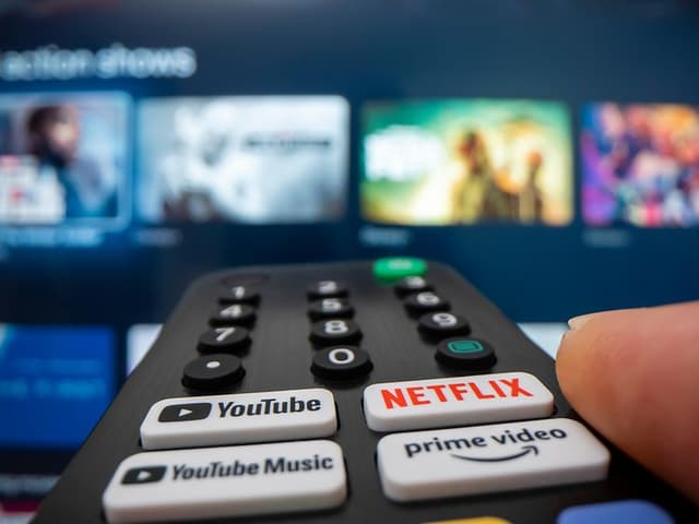 Fjernbetjening med Netflix -, Youtube- og Amazonknapper, peget mod et tv