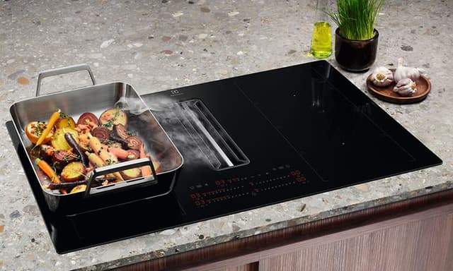 Electrolux ComboHob induktiotaso liesituulettimella ja vihanneksia paistumassa sivussa