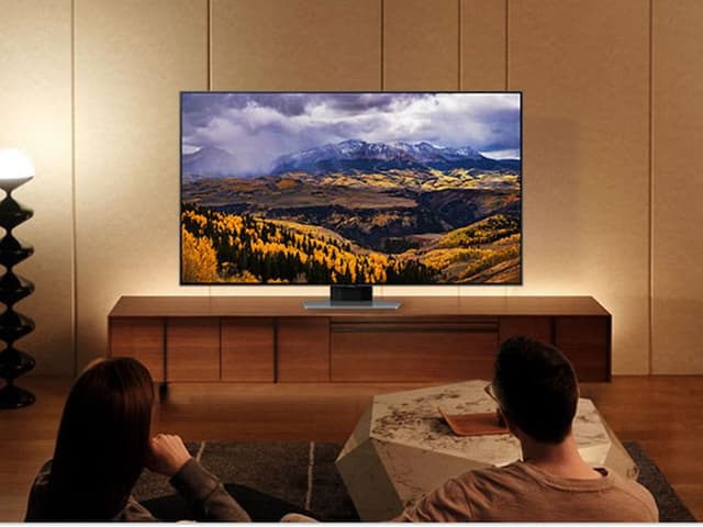 Pariskunta katselee Samsung-televisiota ja nauttivat TV-kokemuksesta voimistavista väreistä