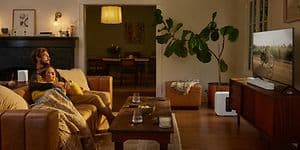 Hvid Sonos Beam 2 der står foran et tv i en stue med dæmpet belysning