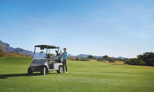 Mand med et smartwatch på håndleddet vælger en golfkølle på en golfbane