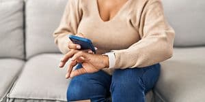 Kvinde der sidder med en smartphone og et smartwatch på håndleddet