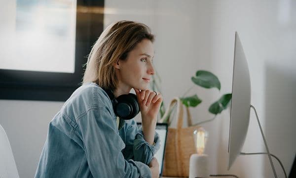 woman with headphones in front of PC