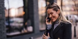 Kvinde der går og smiler imens hun snakker i telefon