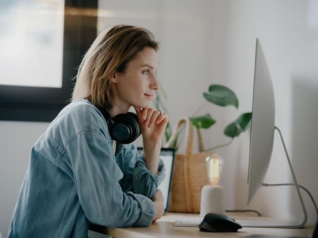 Kvinde med hovedtelefoner foran en PC