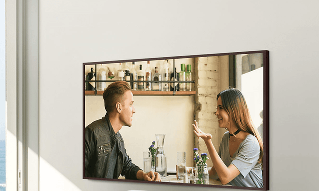 Samsung The Frame TV som henger på vegg og viser mann og kvinne