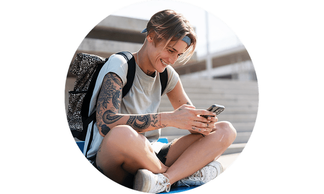Teenager der sidder ude og solen og bruger sin smartphone