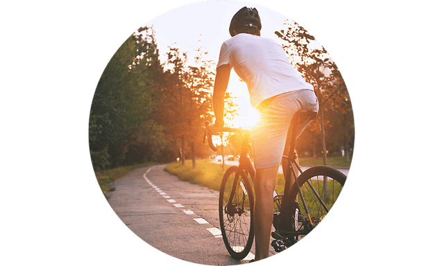 Mand der cykler på sin cykel ved solnedgang