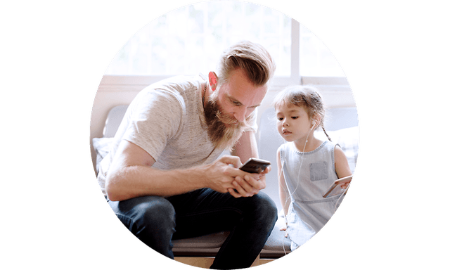 Pappa och liten dotter sitter i en soffa och kollar pappas telefon