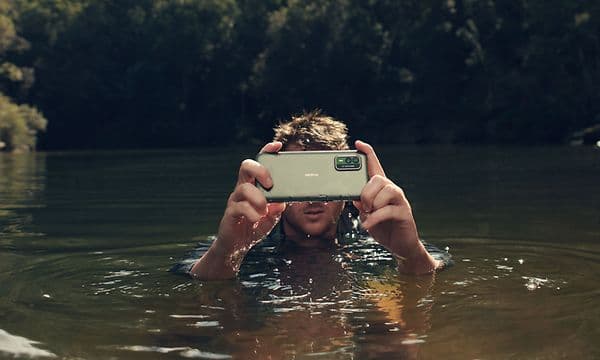 Mand tester NokiaXR21-telefon, mens han er i vandet