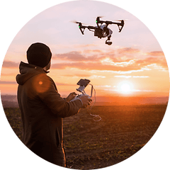 Mand der flyver med en drone ved solnedgang