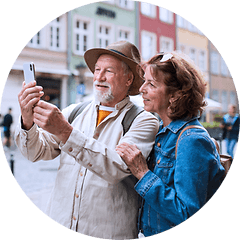 Eldre par står i en bygate og tar en selfie med mobilen sin