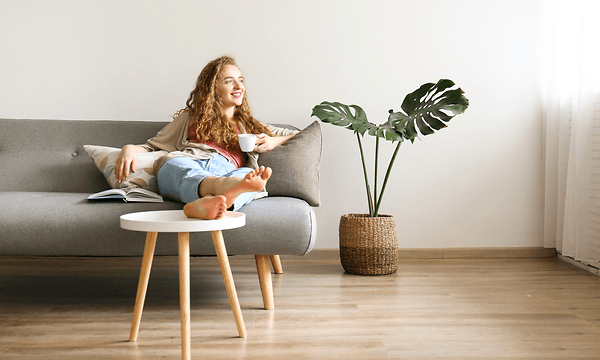 Curly haired woman relaxing with a cup of coffee on the couch at home