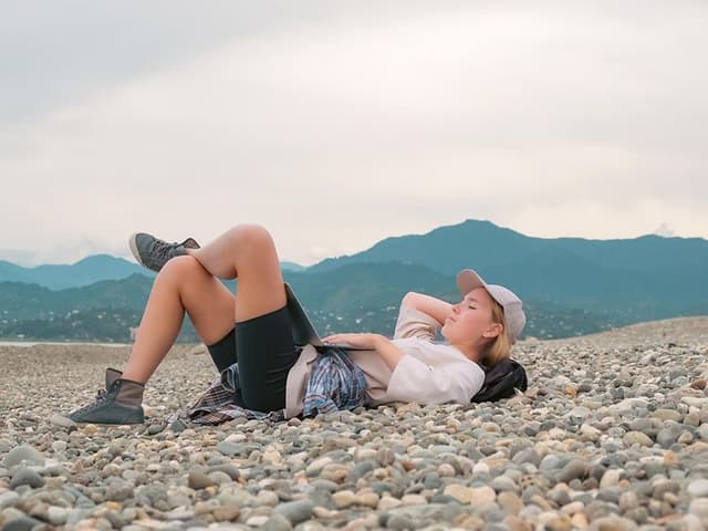 Kvinne som ligger på stranden og slapper av med en laptop
