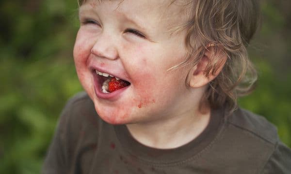Child with strawberry stains on his dark green shirt