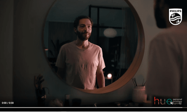 Skärmdump från video om Philips Hue med en man framför en rund spegel. 
