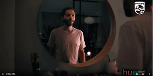 Skärmdump från video om Philips Hue med en man framför en rund spegel. 