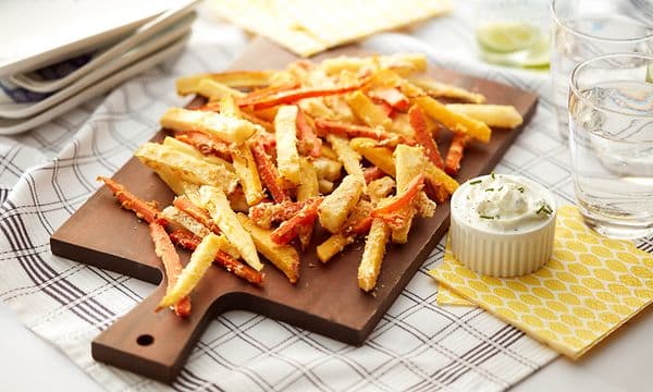 Et fat med crispy pommes frites og dip på et bord