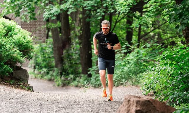 mann som løper på grus med treningsklokke og solbriller