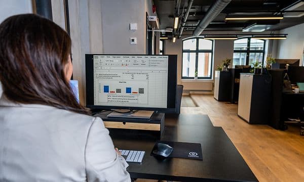 Nainen työskentelee tietokoneellaan avokonttorissa