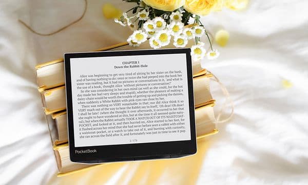 Pöydällä oleva Pocketbook E-book e-kirjan lukulaite sekä kukkia maljakossa sen vieressä