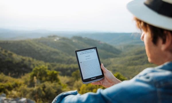 En mann som ser på sin Pockebook med fjell i bakgrunnen