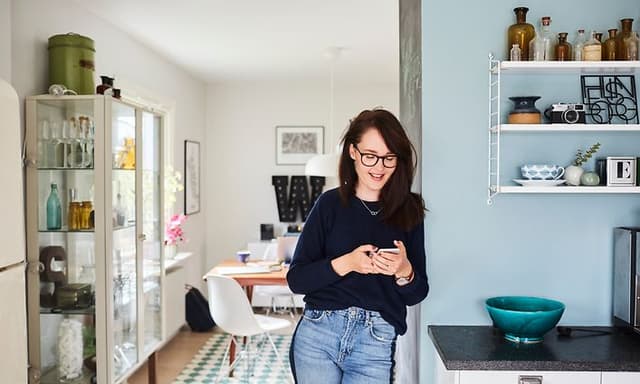 Woman standing in kitchen while on her phone