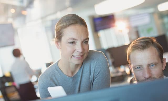 B2B - Telecom - Man and woman looking at a screen in open office landscape