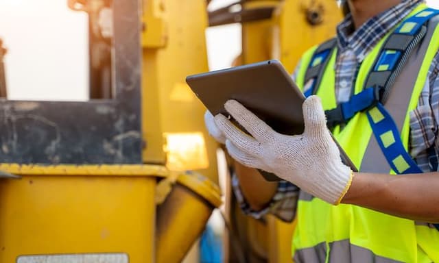 B2B - Tech Gadgets - Construction worker wearing protective gloves checking his tablet