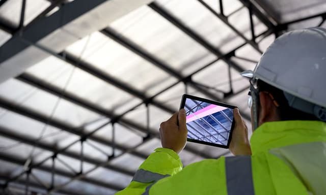 B2B - Tech Gadgets - Worker wearing a hardhat taking a picture of construction with tablet