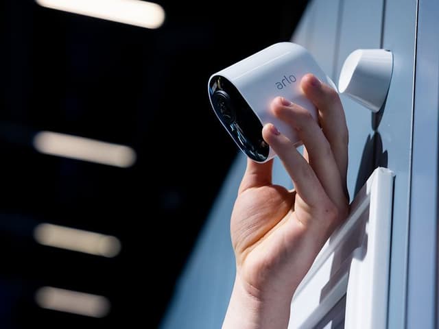 Hand adjusting surveillance camera on wall