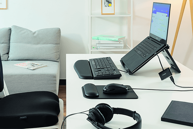 Hjemmekontor med bærbar PC i stativ, eksternt tastatur, trådløs mus og hodetelefoner