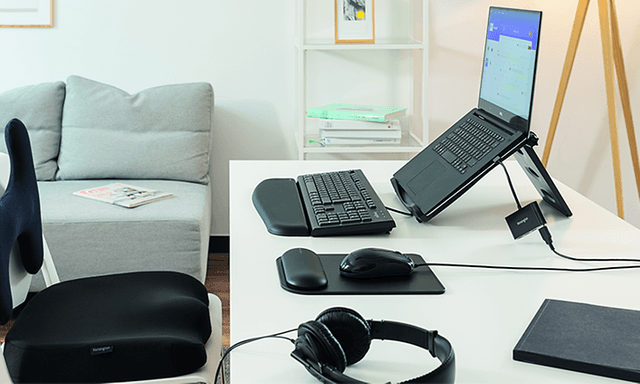 Hjemmekontor med bærbar PC i stativ, eksternt tastatur, trådløs mus og hodetelefoner